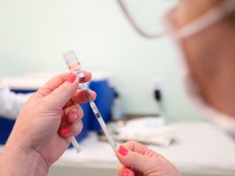 Profissional da saúde com vacina em suas mãos