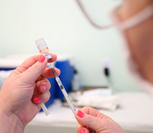 Profissional da saúde com vacina em suas mãos