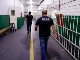Funcionários caminhando dentro de complexo penitenciário