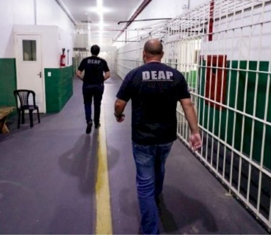 Funcionários caminhando dentro de complexo penitenciário
