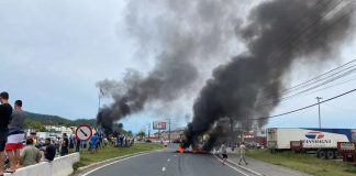 rodovia bloqueada com objetos pegando fogo