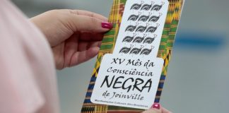 Mulher segura panfleto sobre o XV mês da consciência negra de Joinville