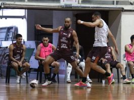Treino do JEC Futsal. Daniel e Pepita disputam bola em quadra. Ao fundo, Renatinho conversa com Gabriel Cândido e Dani Shiraishi conversa com membro da comissão técnica.