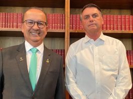 Governador eleito de Santa Catarina à esquerda e presidente Jair Bolsonaro à direita. Os dois estão em frente a uma estante com livros vermelhos.