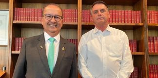 Governador eleito de Santa Catarina à esquerda e presidente Jair Bolsonaro à direita. Os dois estão em frente a uma estante com livros vermelhos.