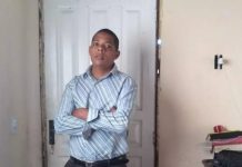 homem em pé de braços cruzados usando camiseta social