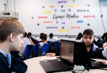 alunos sentados em uma mesa circulando com computadores