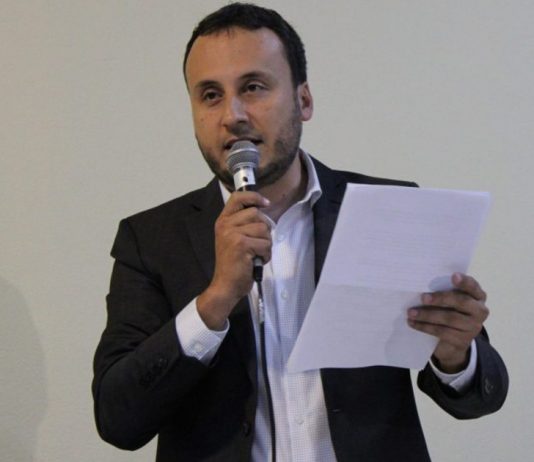 novo presidente do JEC falando ao microfone com uma folha na mão