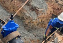 trabalhador dentro d eum buraco cavado na terra com um grande tubo