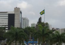 previsão do tempo em joinville. céu nublado no centro com a bandeira do brasil esvoaçando