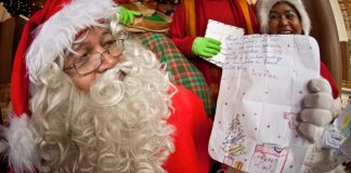 Saiba como adotar cartinhas na campanha Papai Noel dos Correios em Joinville Papai Noel dos Correios segura cartinha na mão