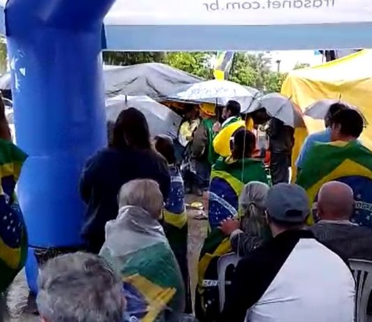 sob chuva, manifestantes de verde e amarelo protestam em joinville