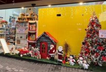 fachada de uma loja decorada com itens de natal como arvore, casa do papai noel, papai noel, boneco de neve e pisca-pisca