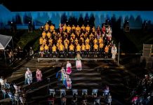 atores em pé, em um palco, durante uma apresentação