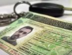 Carteira Nacional de Habilitação com chave de carro ao fundo