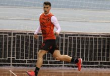 Gabriel Penezio ala/pivô do JEC Futsal corre em quadra. Ao fundo, o preparado de goleiros do JEC Futsal, Fred Antunes, observa.