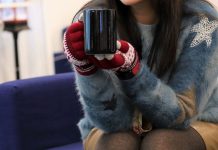 moça com roupas de inverno segurando xícara de café com as duas mãos
