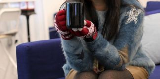 moça com roupas de inverno segurando xícara de café com as duas mãos