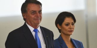 O ex-presidente Jair Bolsonaro sorri acompanha de sua esposa Michelle Bolsonaro