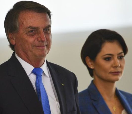 O ex-presidente Jair Bolsonaro sorri acompanha de sua esposa Michelle Bolsonaro