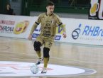 O atleta Pato domina a bola no meio da quadra de futsal, ele utiliza um uniforme dourado do JEC Futsal.