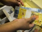 Pessoa segura com as mãos duas notas de R$ 100 e uma nota de R$ 20