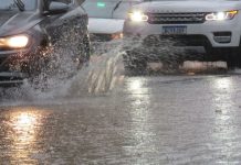 carros passando por rua alagada em joinville